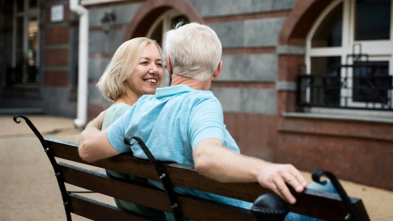 Älteres Paar genießt seine Zeit auf einer Bank im Freien.
